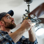 A photograph of a skilled lighting contractor carefully inspecting and replacing parts on a hunter ceiling fan
