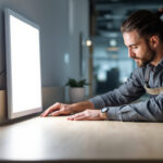 A photograph of a lighting contractor installing or showcasing a 2x2 led panel light in a modern office or commercial space
