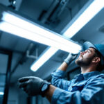 A photograph of a lighting contractor expertly replacing a fluorescent tube with an led equivalent in a commercial setting
