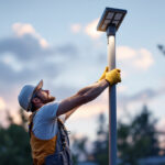A photograph of a lighting contractor expertly installing a sleek solar pole lamp in an outdoor setting
