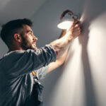 A photograph of a lighting contractor skillfully replacing a canned light fixture in a modern home setting
