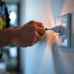 A photograph of a lighting contractor efficiently installing a single plug outlet in a well-lit residential setting