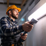 A photograph of a lighting contractor installing or demonstrating a 4-foot fluorescent tube light in a commercial or residential setting