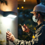 A photograph of a lighting contractor installing a light sensor in an outdoor setting