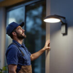 A photograph of a lighting contractor installing a dusk to dawn lamp in an outdoor setting