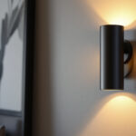 A photograph of a stylish modern black cylinder wall sconce illuminated in a contemporary interior setting