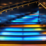 A photograph of a beautifully illuminated staircase showcasing various lighting styles and fixtures