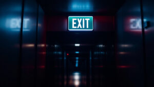 A photograph of a well-lit emergency exit sign in a dimly lit corridor