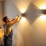 A photograph of a lighting contractor installing led wall fixtures in a modern interior space
