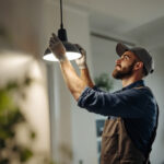 A photograph of a lighting contractor expertly installing or adjusting a modern lighting fixture in a well-lit interior space
