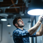 A photograph of a lighting contractor skillfully installing or adjusting modern