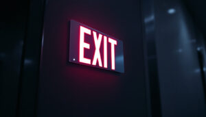 A photograph of a well-lit exit sign in a dimly lit environment