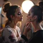 A photograph of a makeup artist applying cosmetics in a well-lit studio