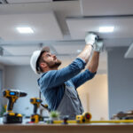 A photograph of a lighting contractor skillfully installing modern drop ceiling panels with integrated lighting fixtures