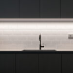 A photograph of a well-lit kitchen showcasing under cabinet lighting with an integrated outlet