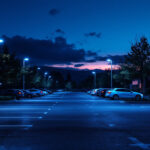 A photograph of a well-lit parking lot at dusk