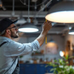 A photograph of a skilled lighting contractor carefully measuring and adjusting various light fixtures in a well-lit workspace
