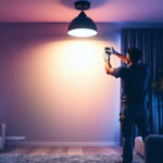 A photograph of a lighting contractor installing led retrofit can lights in a modern residential space