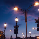 A photograph of a well-lit street scene featuring various types of street light poles