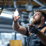 A photograph of a lighting contractor demonstrating the process of replacing a fluorescent bulb with an led bulb in a commercial or residential setting