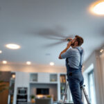 A photograph of a lighting contractor installing ic rated recessed lights in a modern home setting