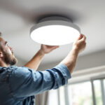 A photograph of a skilled lighting contractor expertly installing a modern recessed light fixture in a stylish home interior