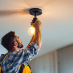 A photograph of a skilled lighting contractor installing a stylish ceiling light fixture in a modern home