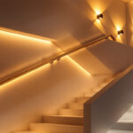 A photograph of a beautifully lit staircase featuring a variety of lighting installations