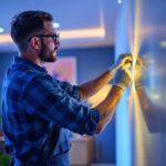 A photograph of a skilled lighting contractor installing vibrant led strip lights in a modern interior setting