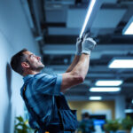 A photograph of a lighting contractor installing flat panel led lights in a modern workspace