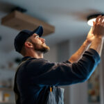 A photograph of a lighting contractor installing or adjusting modern led recessed lighting fixtures in a stylish