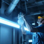 A photograph of a lighting contractor working on the installation of an 8ft fluorescent bulb in a commercial setting