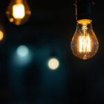 A photograph of a close-up view of a flickering light bulb in a dimly lit room