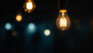 A photograph of a close-up view of a flickering light bulb in a dimly lit room