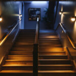 A photograph of a well-lit basement stairwell showcasing various lighting options