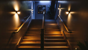 A photograph of a well-lit basement stairwell showcasing various lighting options