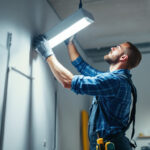 A photograph of a smart lighting contractor skillfully replacing a fluorescent light fixture with an led alternative