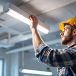 A photograph of a lighting contractor expertly replacing a fluorescent light fixture with an led one