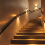 A photograph of a well-lit stairwell featuring modern led lighting fixtures that highlight the architectural details and create a warm