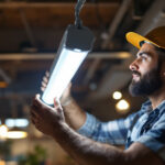 A photograph of a lighting contractor expertly replacing a fluorescent tube with a modern led fixture in a well-lit commercial space