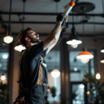 A photograph of a lighting contractor expertly installing or adjusting various lighting fixtures in a commercial or residential setting