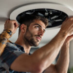 A photograph of a lighting contractor installing or adjusting a 6-inch recessed light trim in a modern home setting
