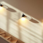 A photograph of a beautifully illuminated staircase wall featuring a variety of stylish wall-mounted light fixtures
