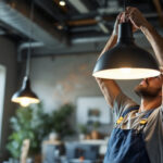 A photograph of a lighting contractor expertly installing a stylish commercial light fixture in a modern workspace