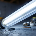 A photograph of a close-up shot of a fluorescent light fixture being retrofitted with led bulbs