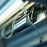 A photograph of a close-up view of a fluorescent light fixture with its ballast exposed