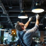 A photograph of a lighting contractor expertly installing nauticus lighting fixtures in a modern commercial space