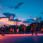 A photograph of a well-lit outdoor basketball court at dusk