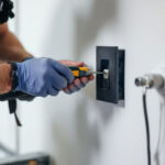 A photograph of a lighting contractor inspecting an outlet box cover installation