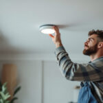 A photograph of a lighting contractor installing 4-inch can lights in a modern residential setting